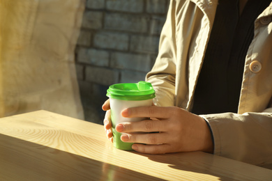 Woman with cup of fresh aromatic coffee at table in cafe