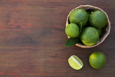 Photo of Fresh ripe limes and wicker basket on wooden table, flat lay. Space for text