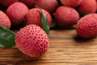 Photo of Fresh ripe lychee fruits on wooden table, closeup. Space for text