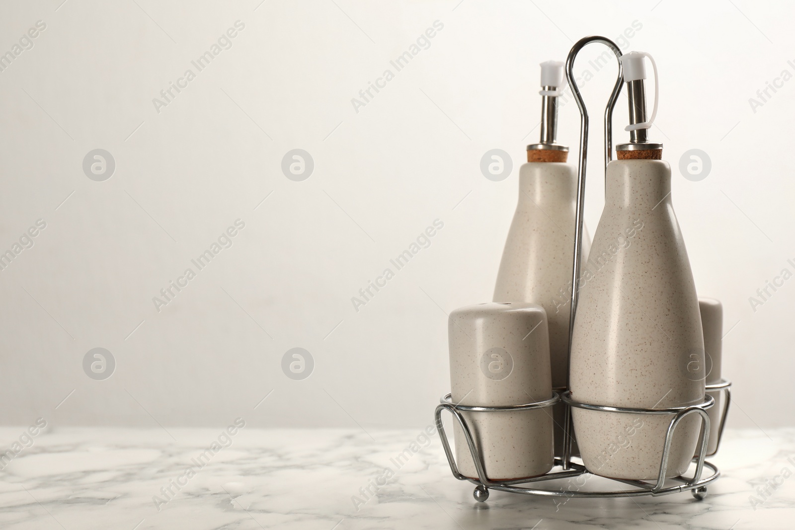 Photo of Sauce bottles with salt and pepper shakers in holder on white marble table. Space for text