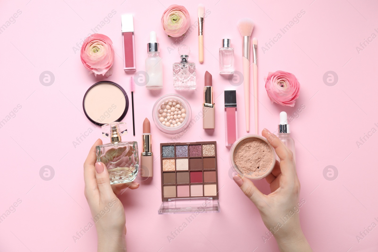 Photo of Woman with different makeup products and beautiful spring flowers on pink background, top view