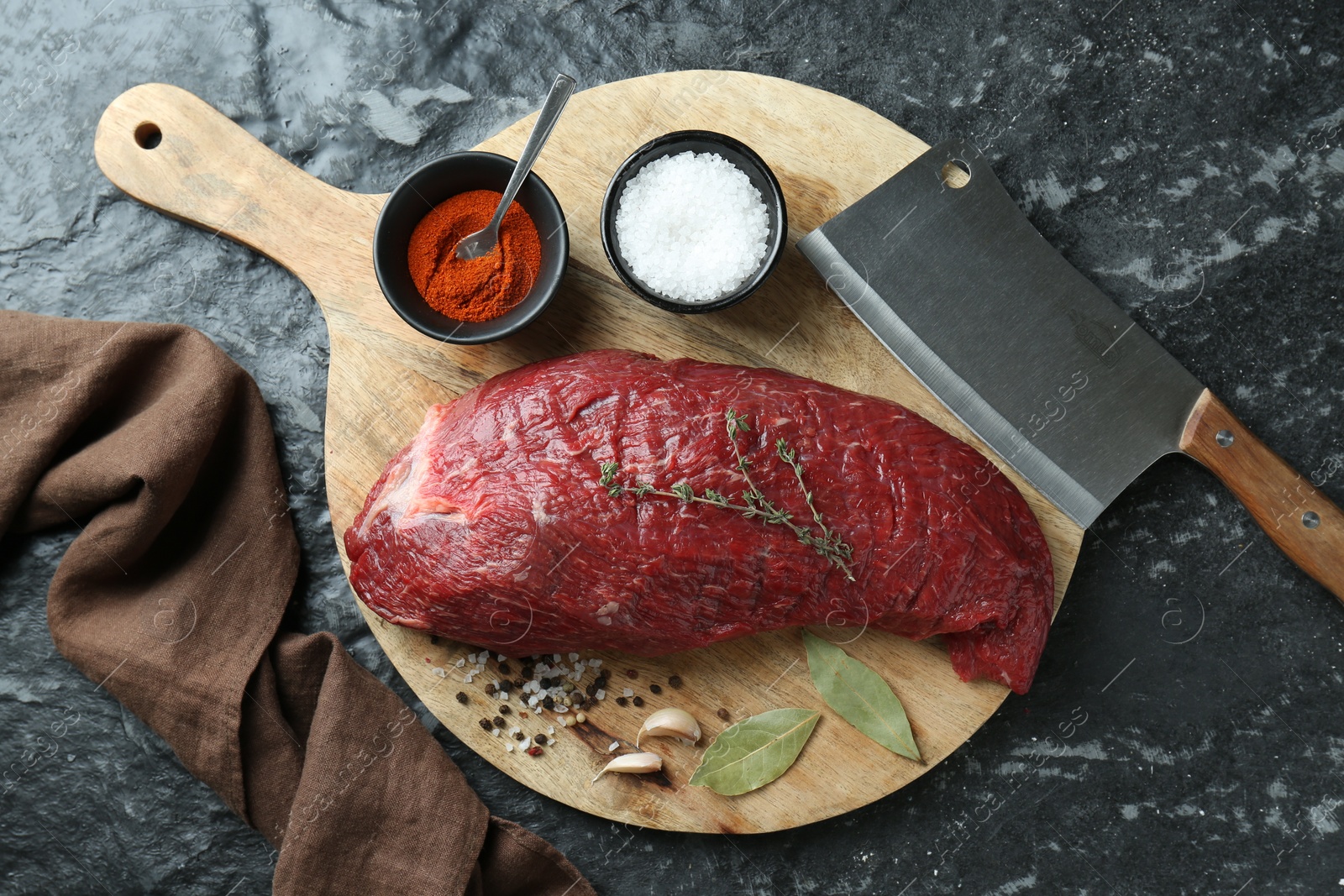 Photo of Piece of raw beef meat, knife and spices on black textured table, flat lay
