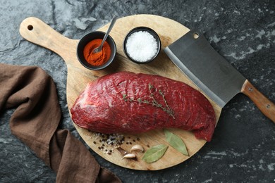 Piece of raw beef meat, knife and spices on black textured table, flat lay