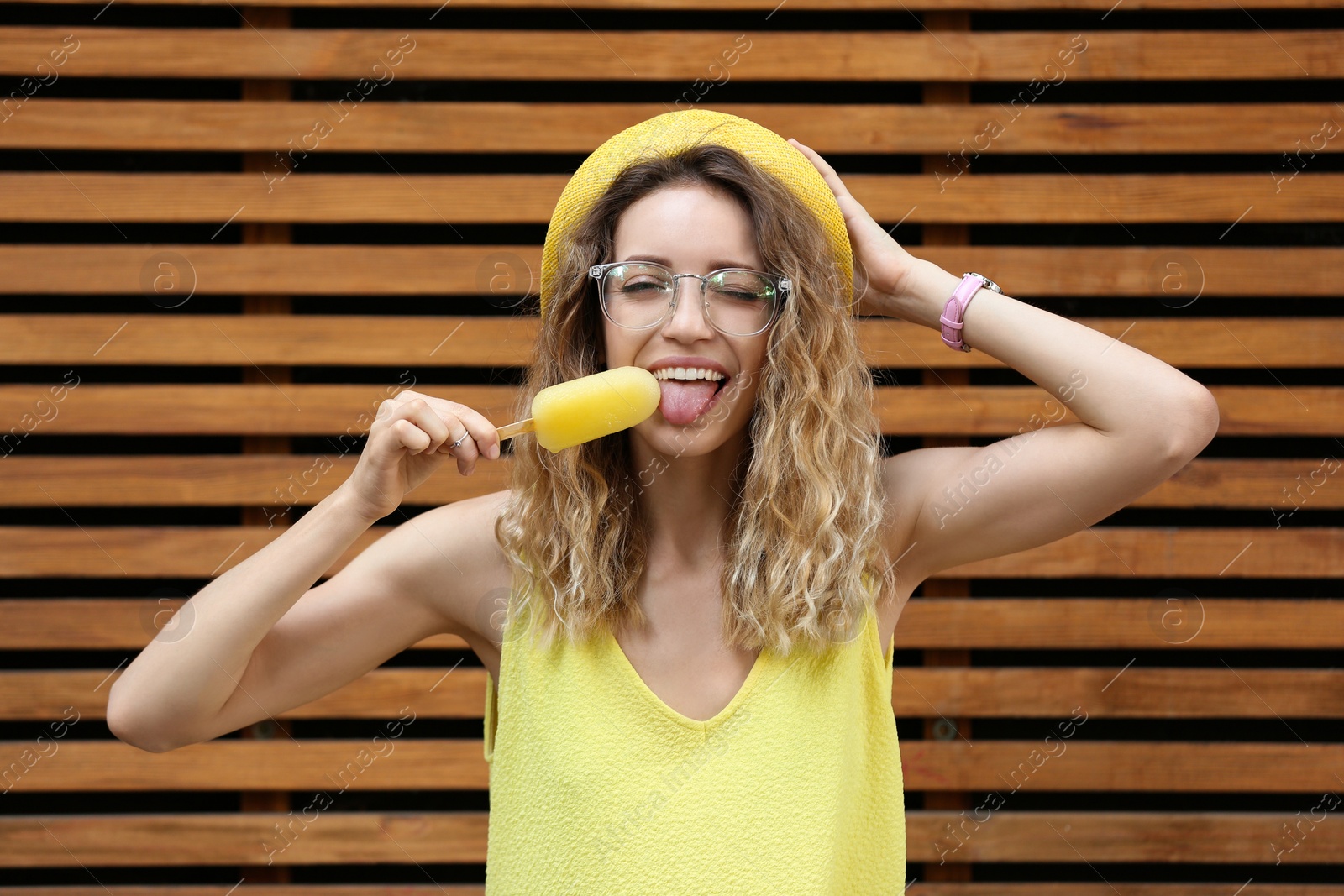 Photo of Happy young woman with delicious ice cream near wooden wall