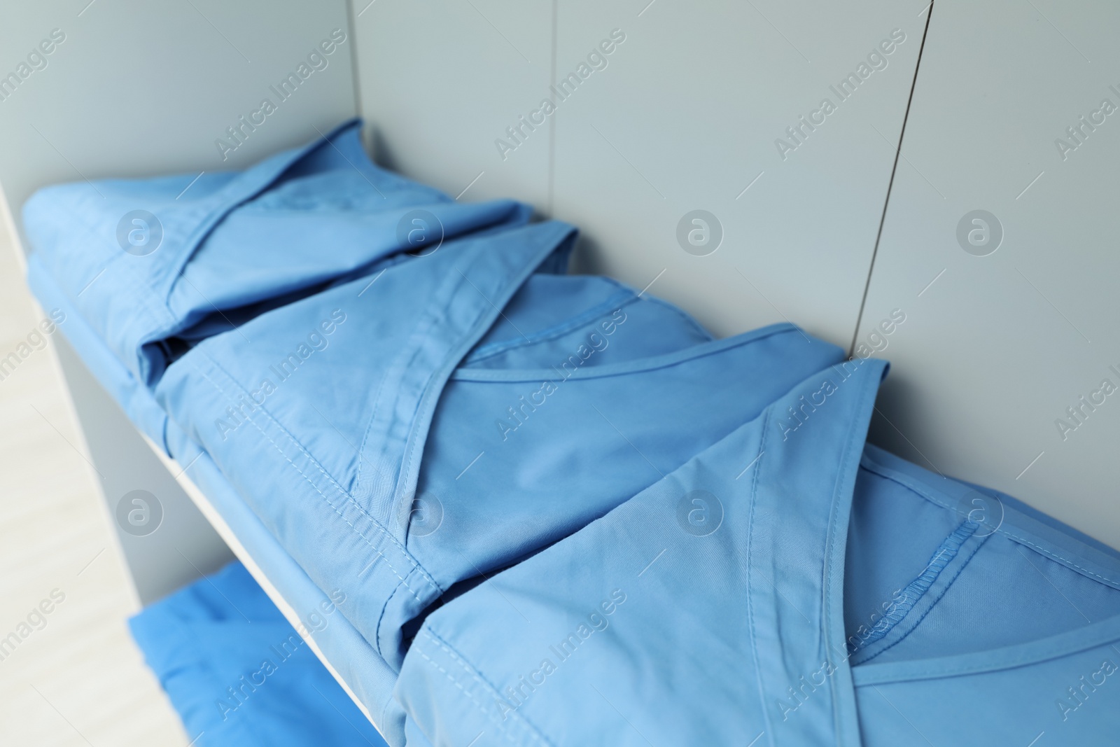 Photo of Light blue medical uniforms on white rack