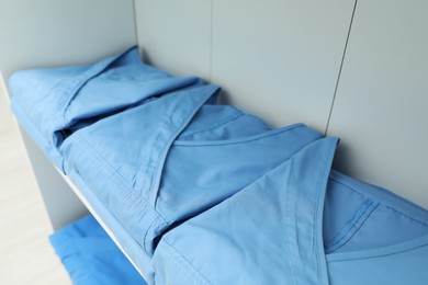 Light blue medical uniforms on white rack