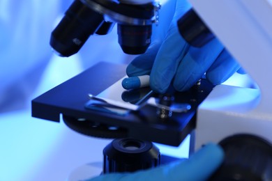 Photo of Scientist examining pill under microscope in laboratory, closeup