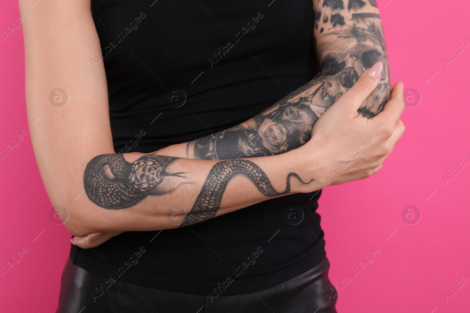 Photo of Woman with tattoos on arms against pink background, closeup