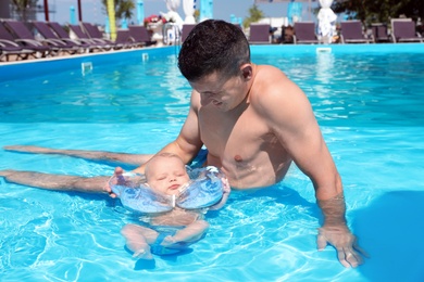 Man with his little baby in swimming pool on sunny day, outdoors