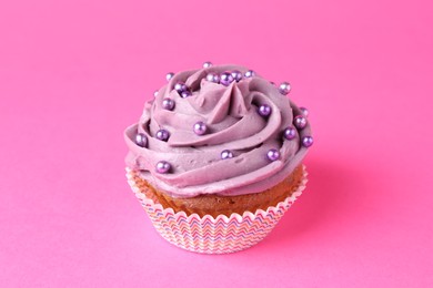 Photo of Delicious cupcake with bright cream and sprinkles on pink background