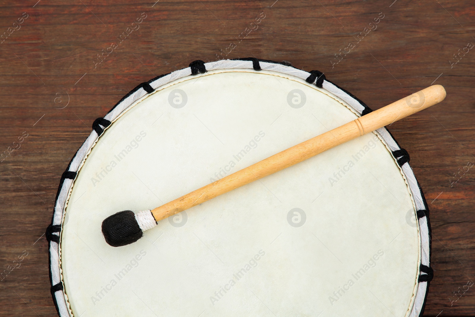 Photo of Modern drum with drumstick on wooden table, top view. Percussion musical instrument