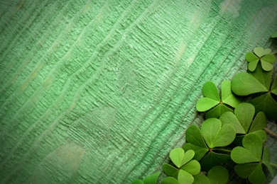 Clover leaves on green wooden table, flat lay with space for text. St. Patrick's Day symbol