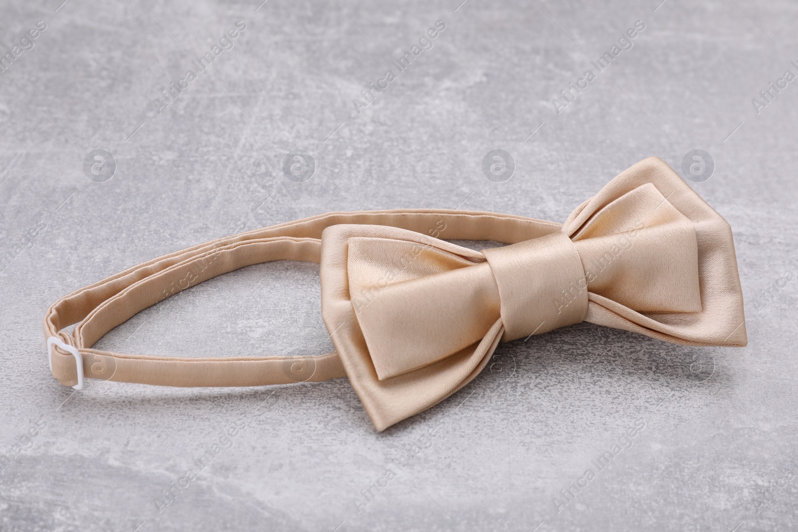 Photo of Stylish beige bow tie on light grey table