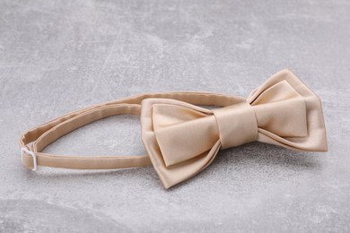 Stylish beige bow tie on light grey table