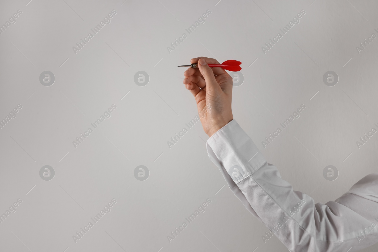 Photo of Businesswoman holding red dart on light background, closeup. Space for text