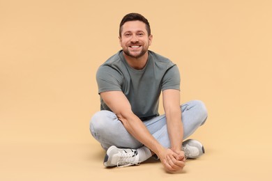 Photo of Happy handsome man sitting on beige background