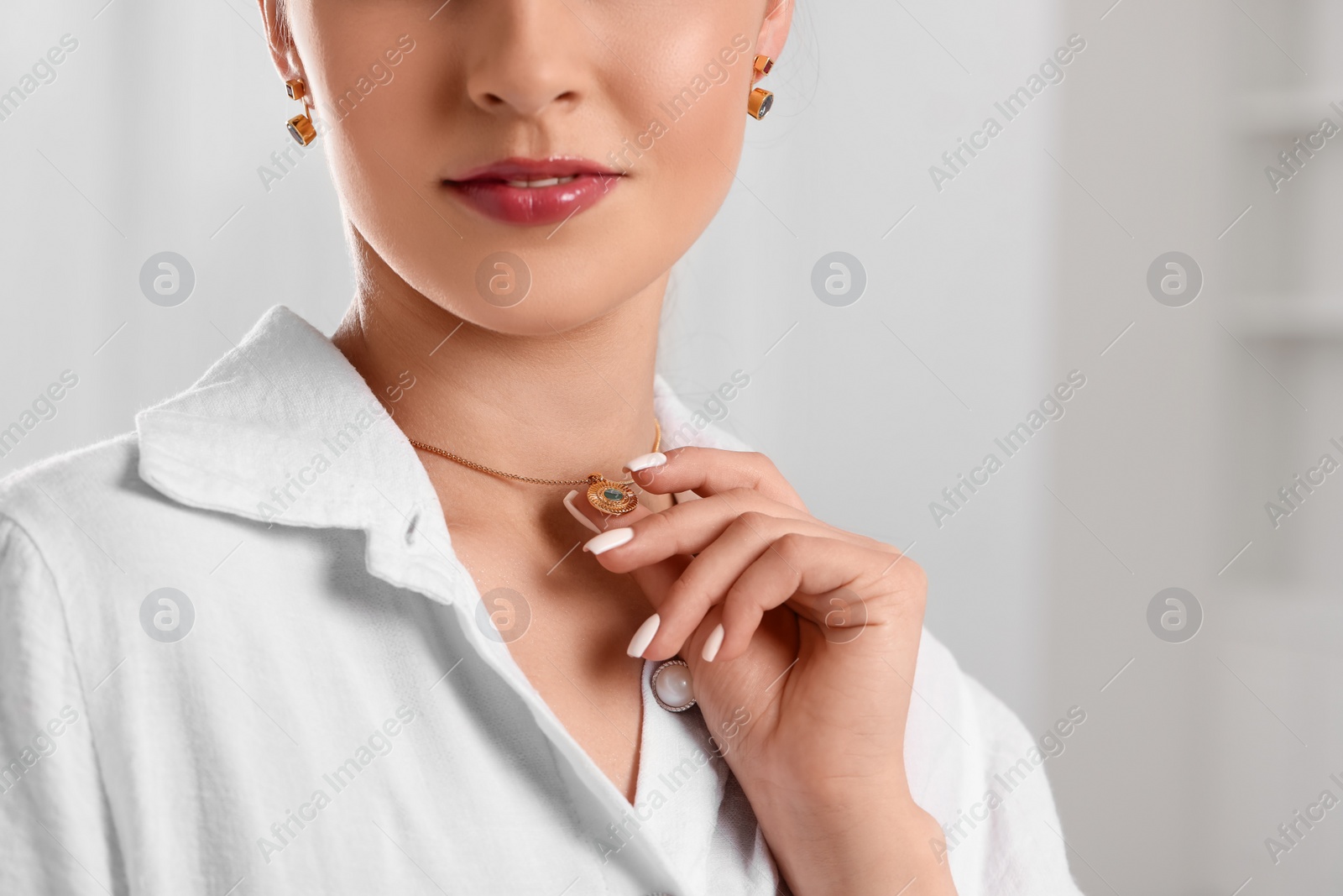 Photo of Beautiful woman with elegant jewelry on light background, closeup. Space for text