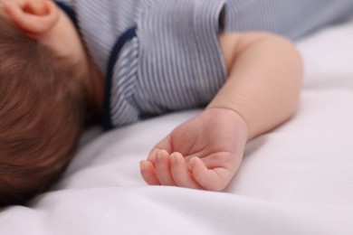 Photo of Newborn baby lying on white blanket, closeup