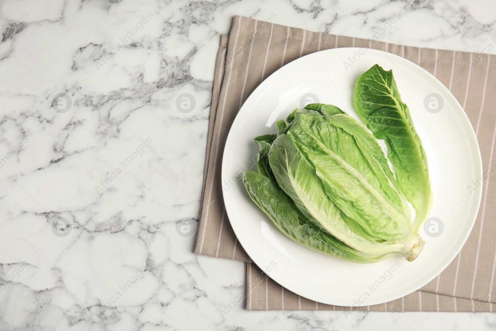 Photo of Plate with fresh ripe cos lettuce on marble table, top view