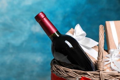 Photo of Gift basket with bottle of wine on color background