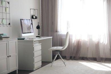 Photo of Comfortable white chair near desk in stylish office interior