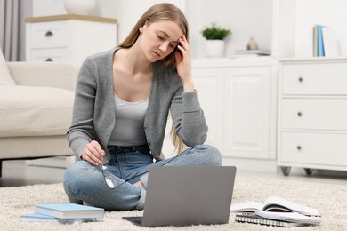 Photo of Overwhelmed young woman sitting with laptop on floor at home