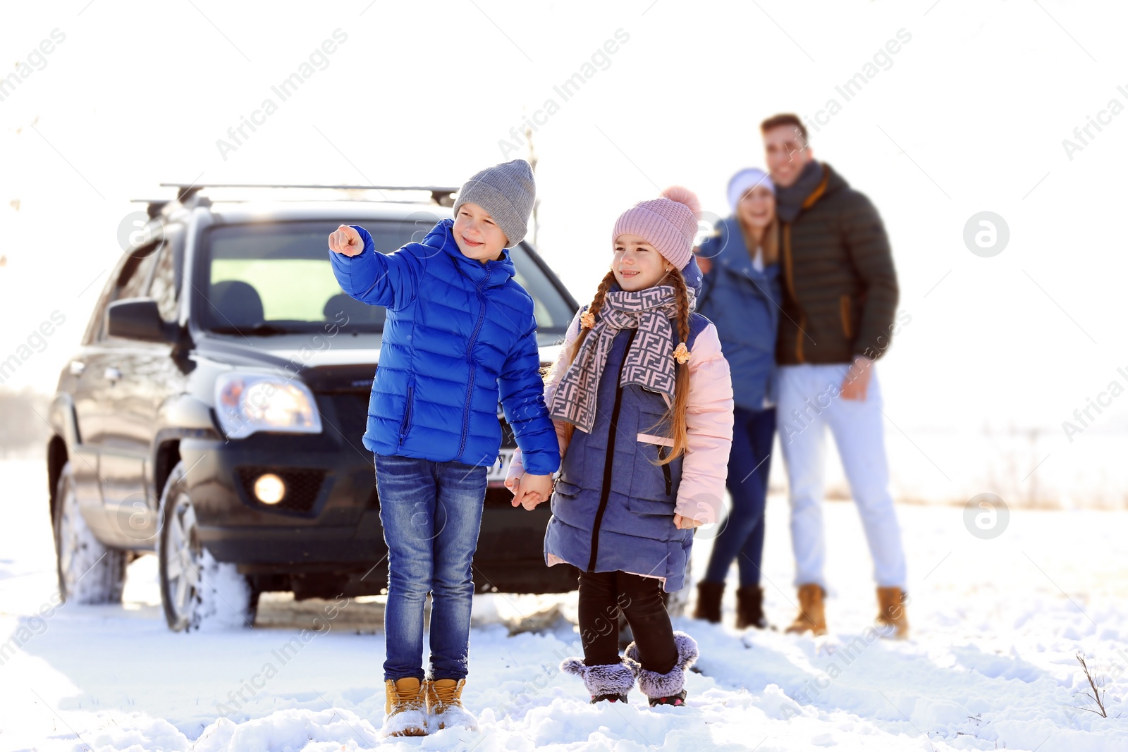 Photo of Cute little brother and sister with parents walking in countryside on winter day