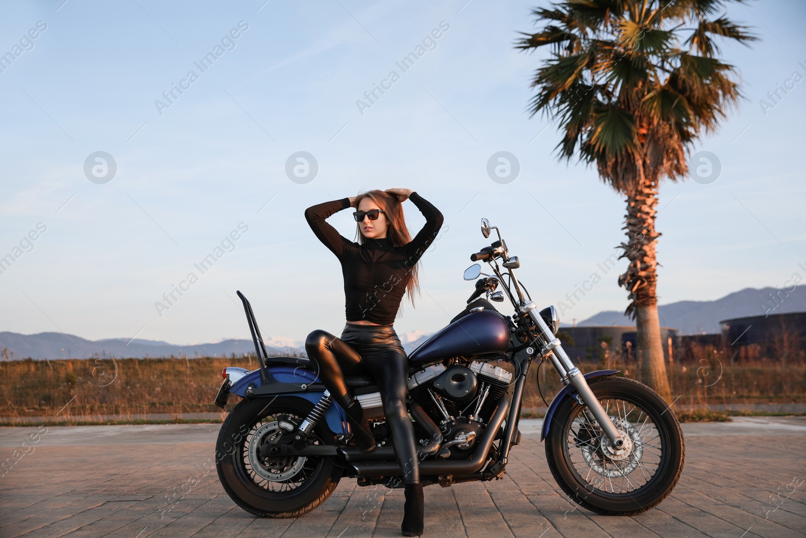 Photo of Beautiful young woman sitting on motorcycle outdoors