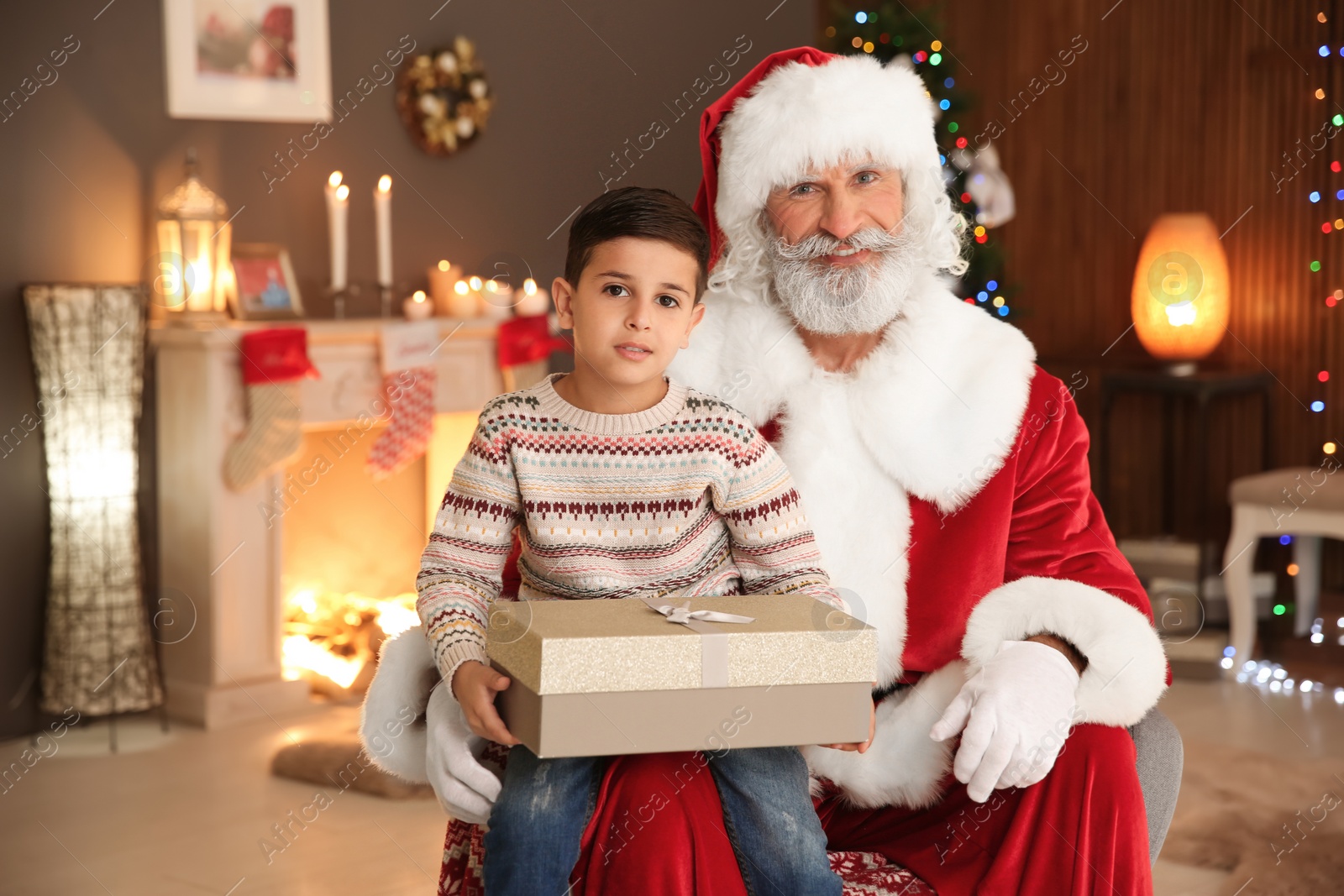 Photo of Little child with Santa Claus and Christmas gift at home