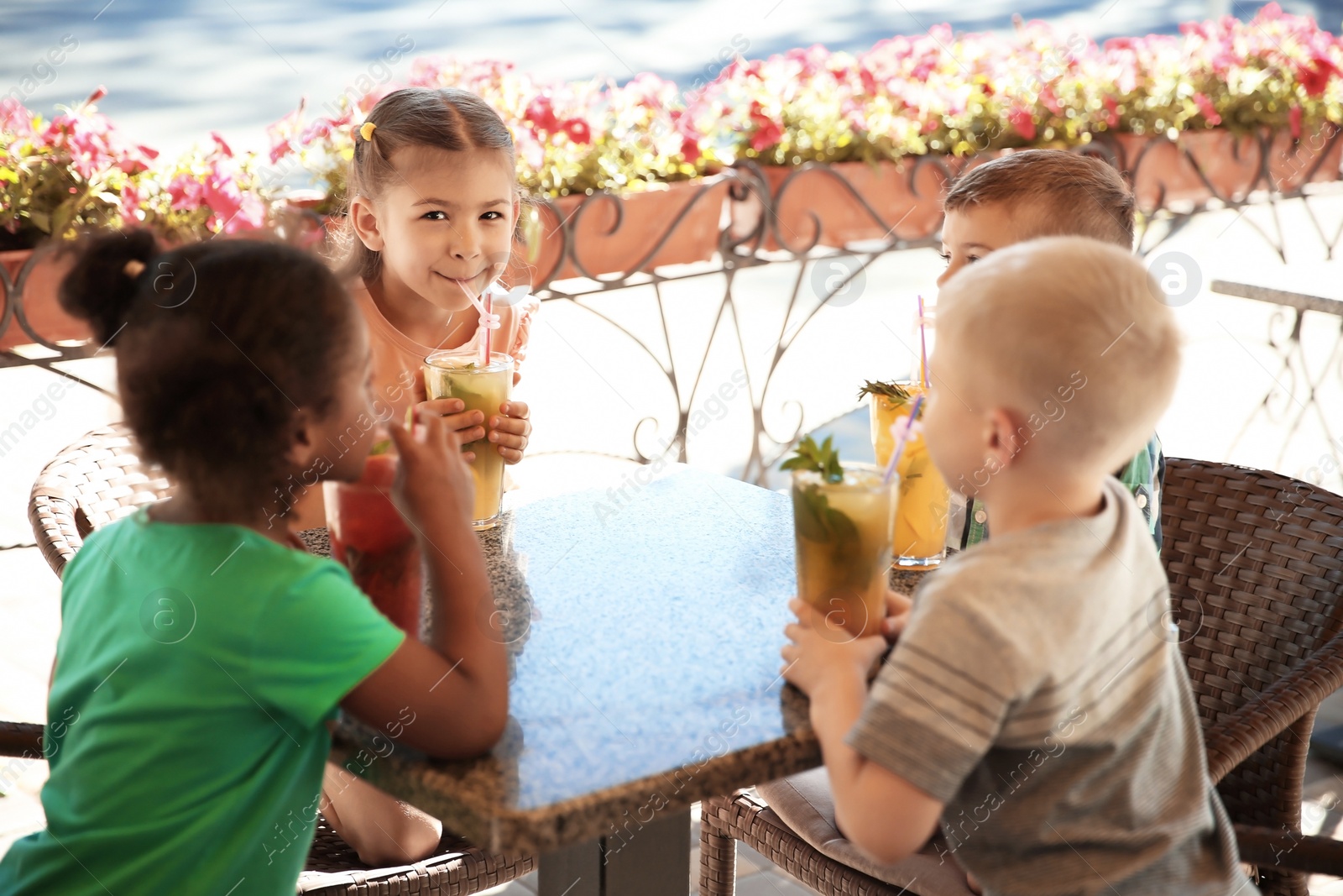 Photo of Cute children with glasses of natural lemonades at table in cafe