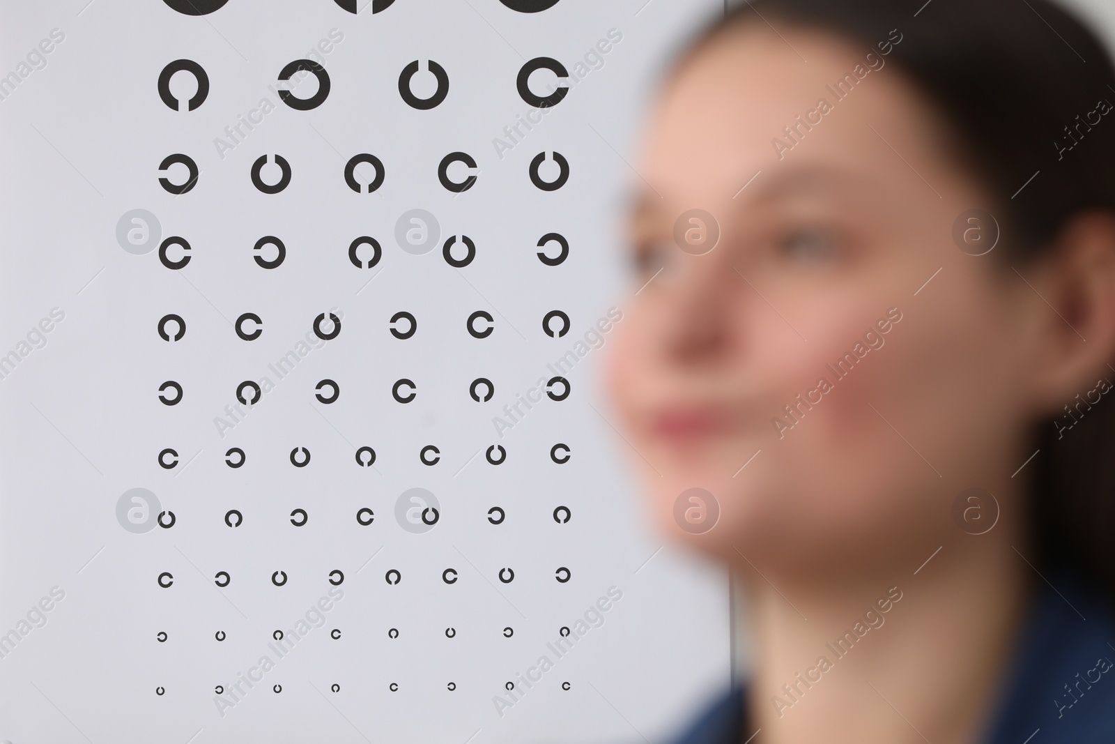 Photo of Young woman against vision test chart, selective focus
