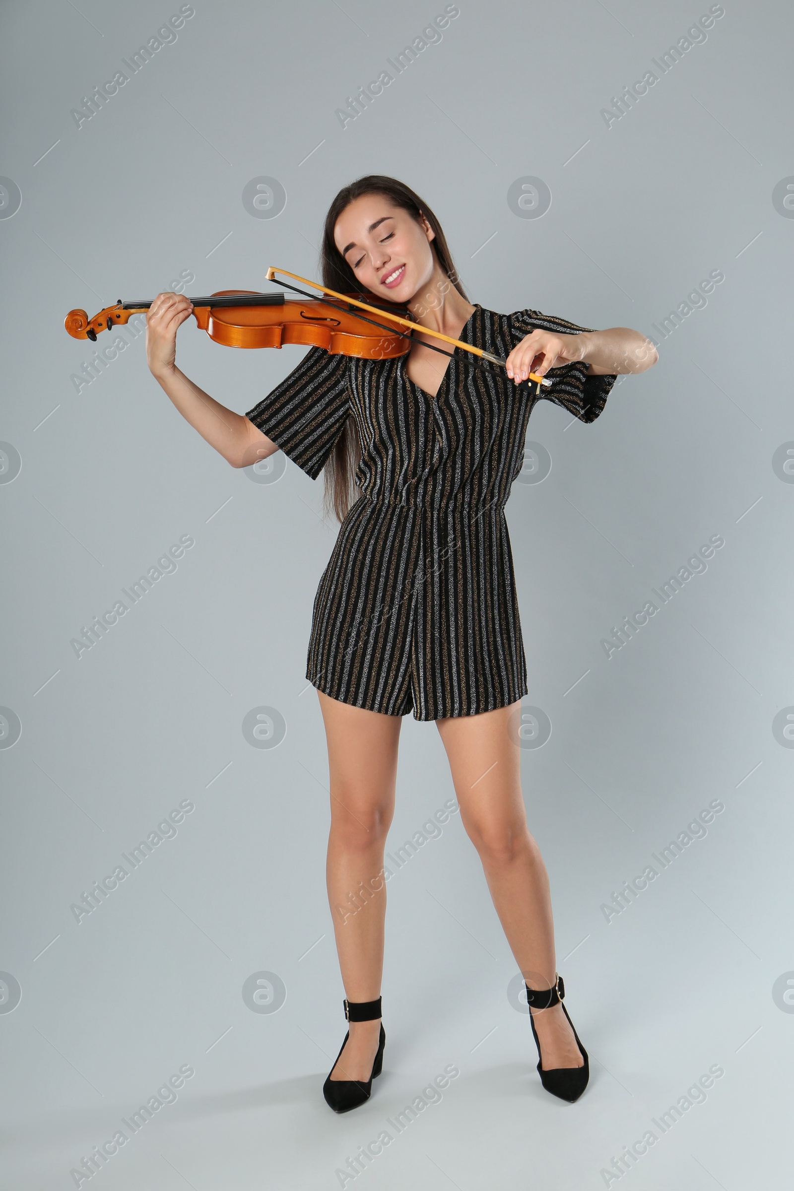 Photo of Beautiful woman playing violin on grey background