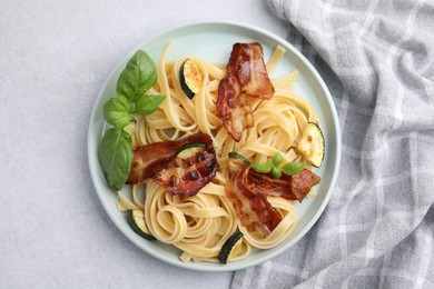 Photo of Tasty pasta with bacon and basil on light grey table, top view