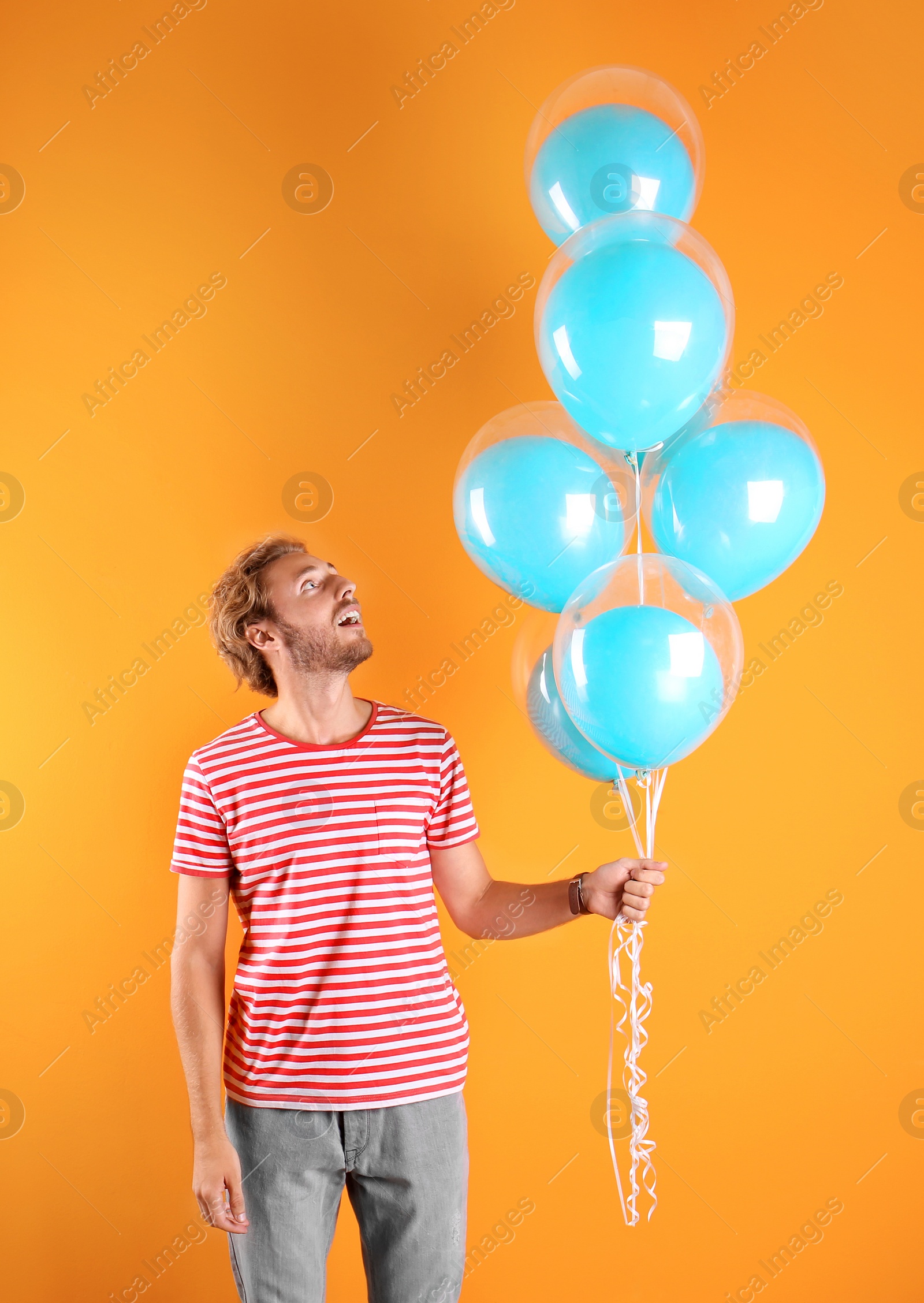 Photo of Young man with air balloons on color background