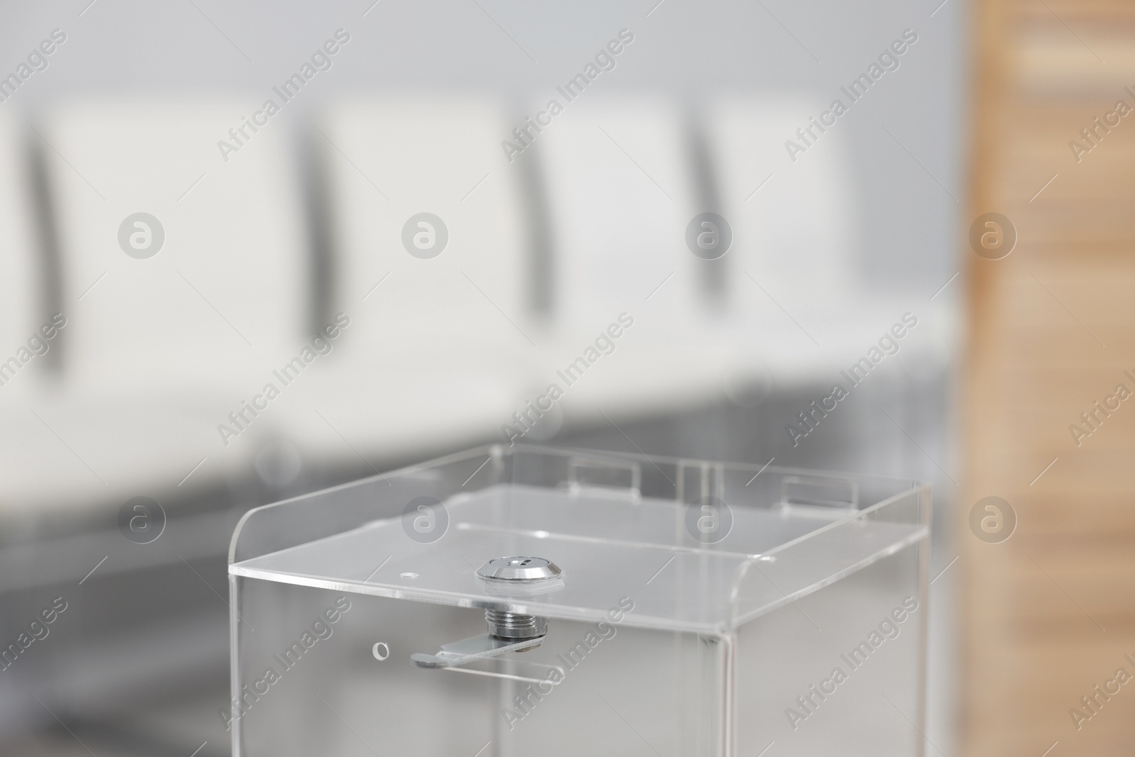 Photo of Transparent ballot box on blurred background, closeup. Space for text