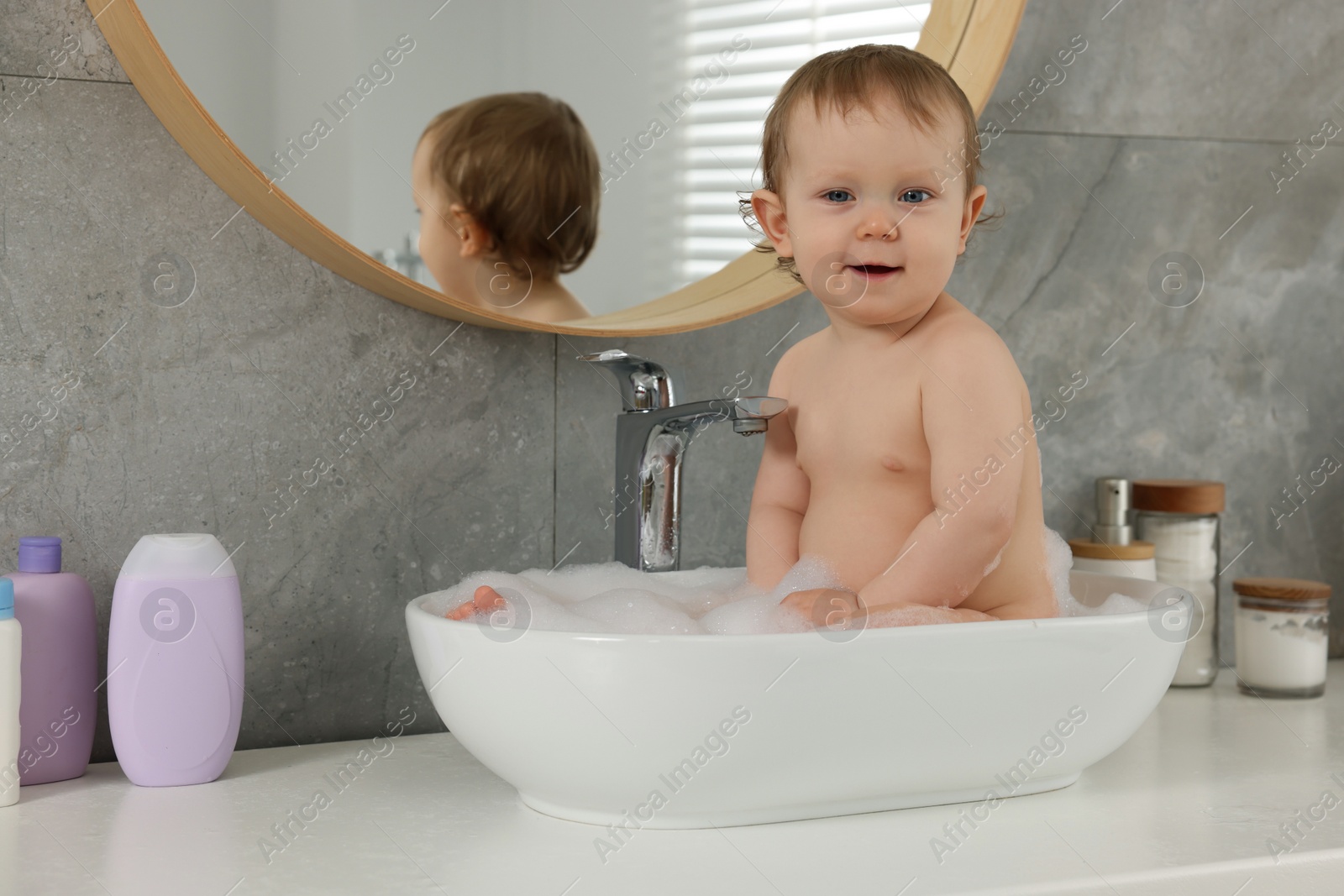 Photo of Cute little baby bathing in sink at home