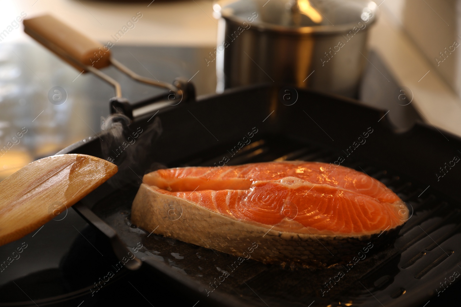 Photo of Frying pan with fresh salmon steak on stove