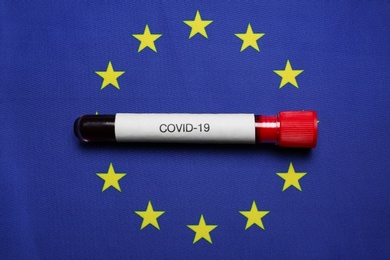 Photo of Test tube with blood sample on European Union flag background, top view. Coronavirus outbreak
