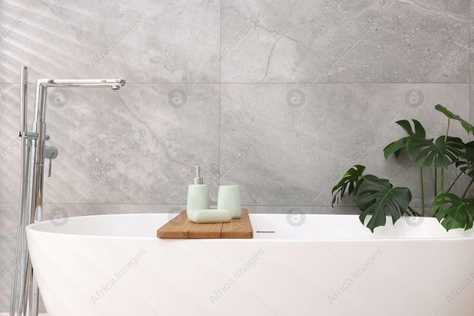 Photo of Set of bath accessories on tub in bathroom