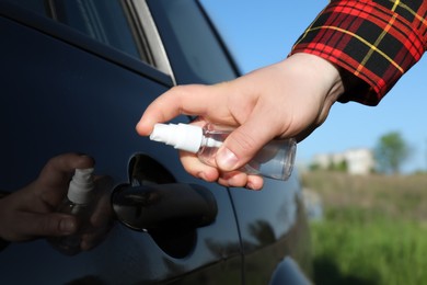 Photo of Closeup view of man disinfecting car door handle outdoors