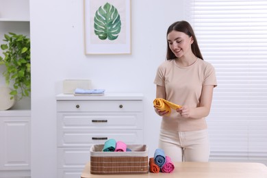 Photo of Young woman rolling shirt in room, space for text. Organizing clothes