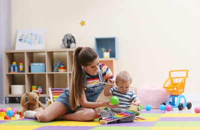 Teen nanny and cute little baby playing with toys at home