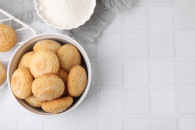 Photo of Tasty sugar cookies in bowl on white tiled table, top view. Space for text