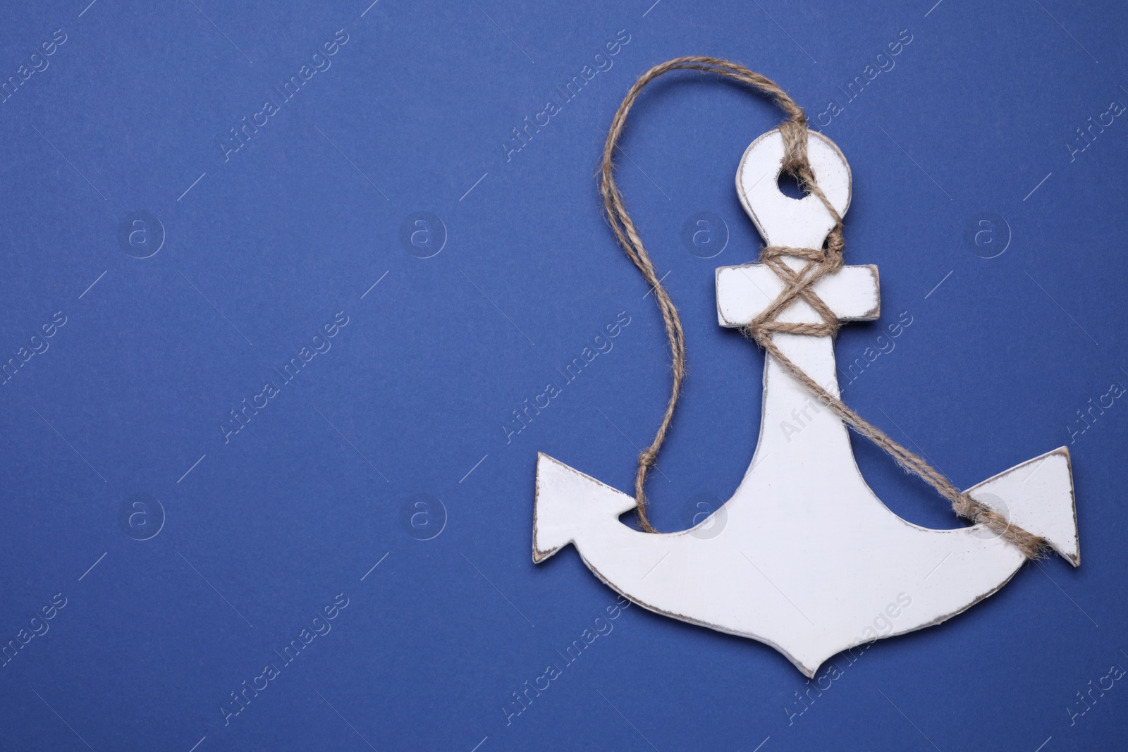 Photo of White wooden anchor figure on blue background, top view. Space for text