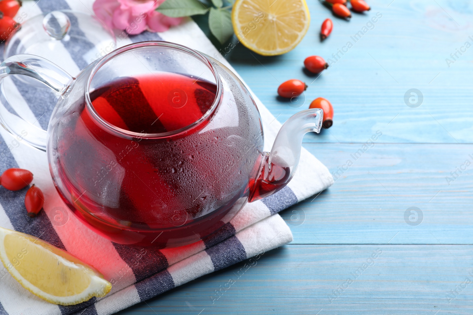 Photo of Fresh rose hip tea and berries on blue wooden table. Space for text