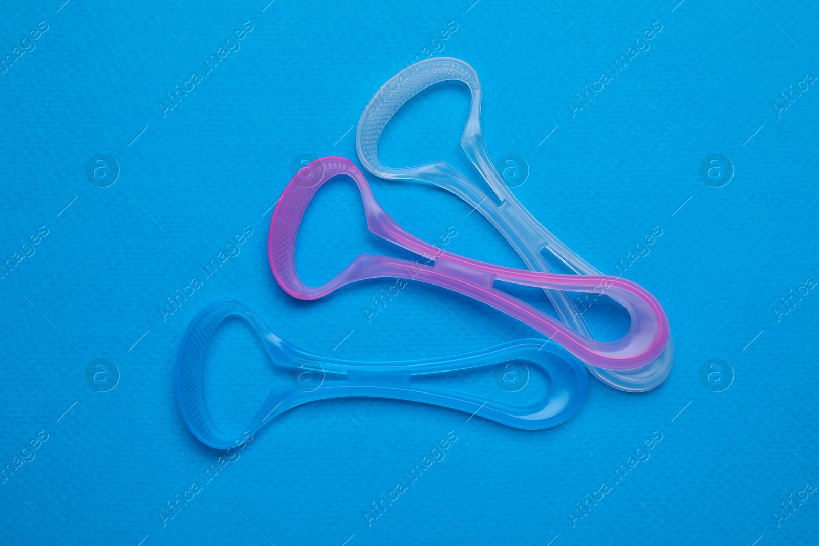 Photo of Tongue cleaners on blue background, flat lay. Dental care