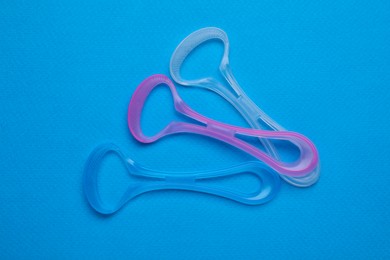 Tongue cleaners on blue background, flat lay. Dental care