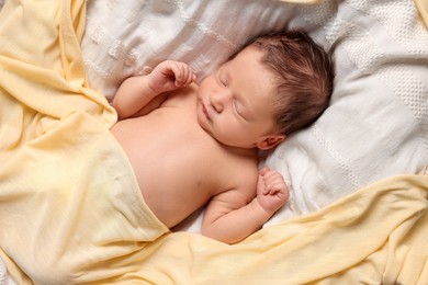 Cute newborn baby sleeping on white blanket, top view