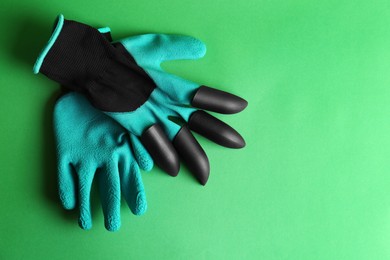 Photo of Gardening gloves on green background, top view. Space for text