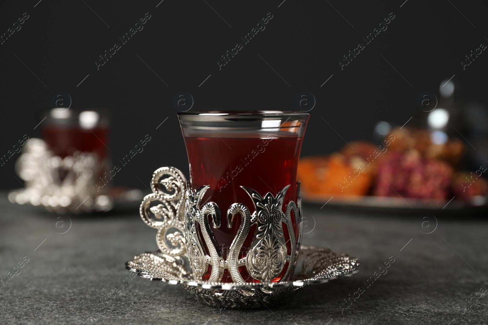 Photo of Glass of traditional Turkish tea in vintage holder on grey table